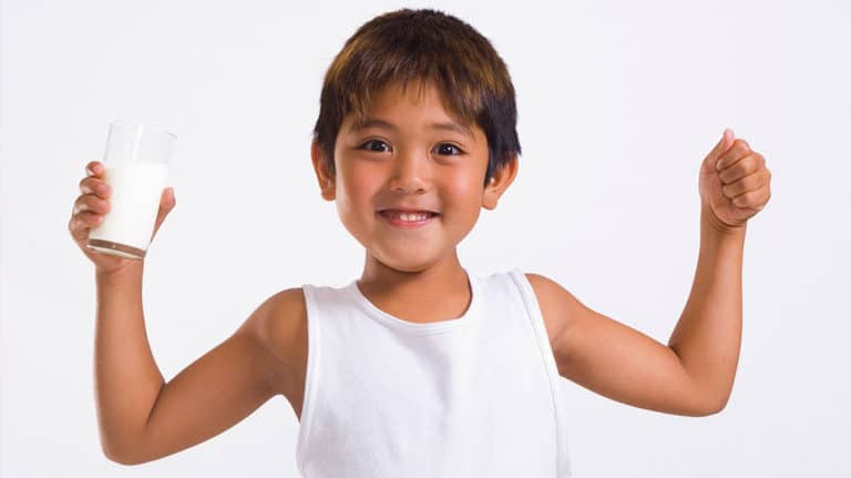 Young child flexing muscles and holding a glass of milk