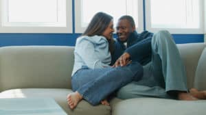 A married couple sits closely on a sofa enjoying each other’s company