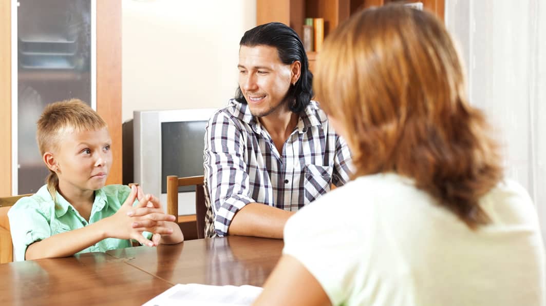 Mom and dad talk with teen at kitchen table
