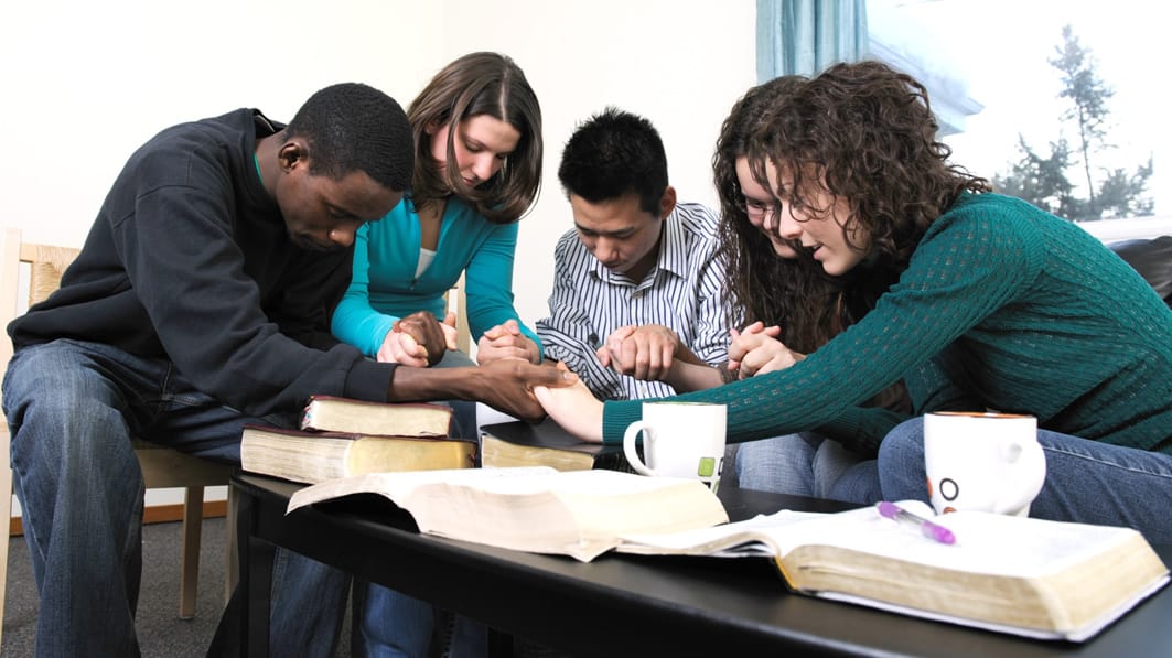 A group of young adults pray together