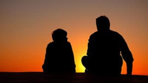 Silhouette of father talking with son with sunset in background