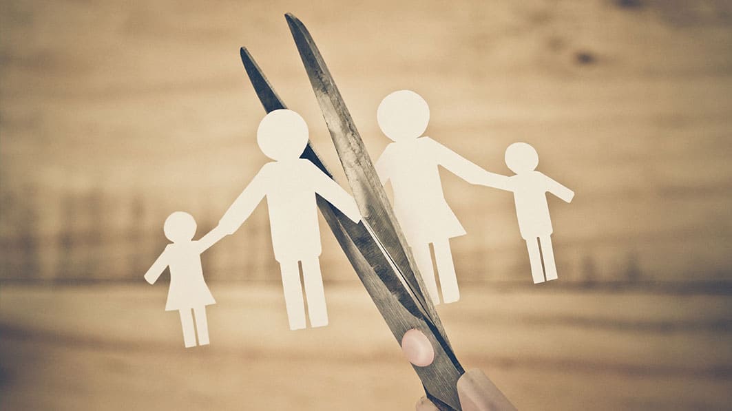 Paper cutout representing a family about to be cut in half with scissors