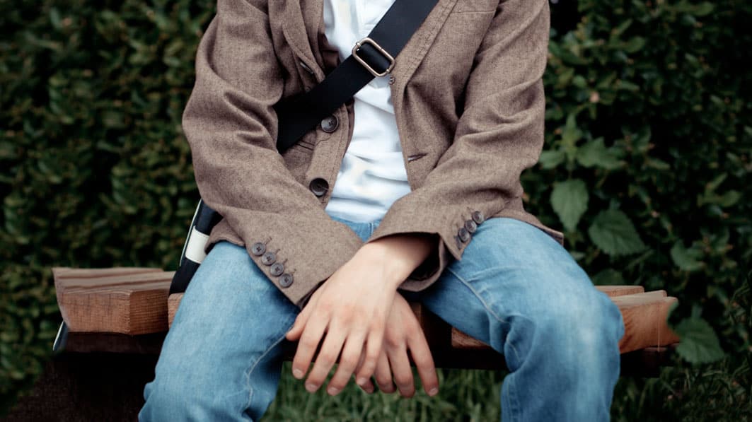 Young man sitting on a bench outside