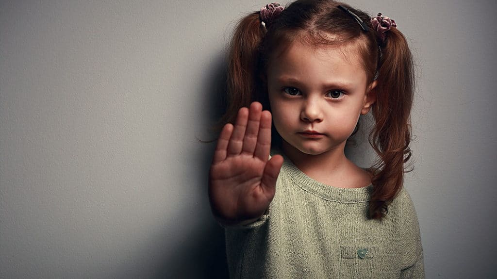 Young girl holding up her hand to communicate "stop"