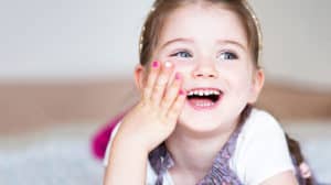 Little girl with painted fingernails and wearing a little gold crown, laughing