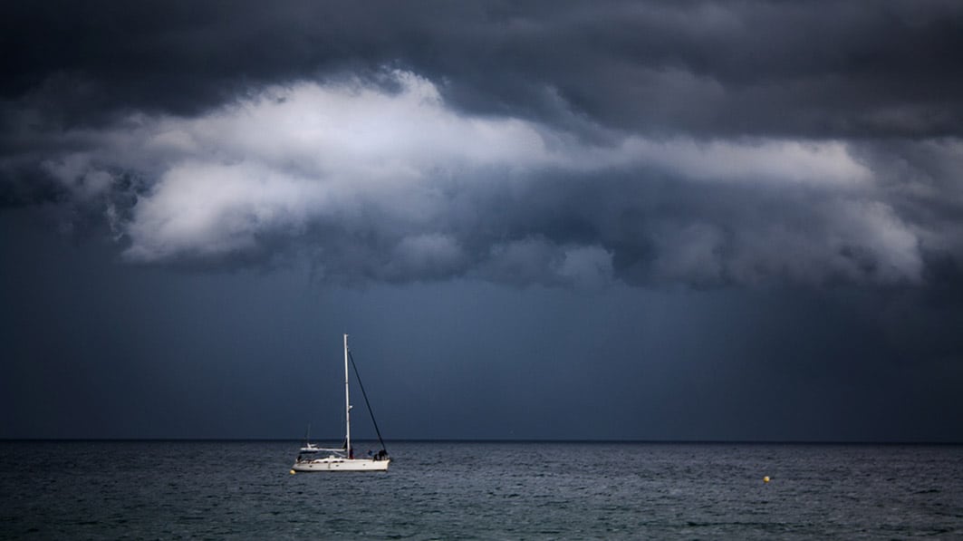 Boat sailing under dark sky and stormy clouds