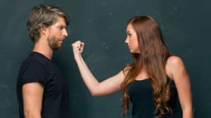 Angry woman threatening a man with her fist near his face