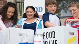 Small group of kids organizing canned food for a food drive