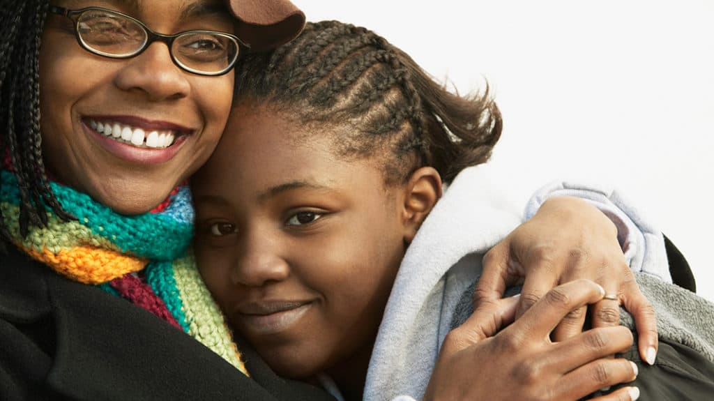 Close up of African American mom hugging her teen daughter