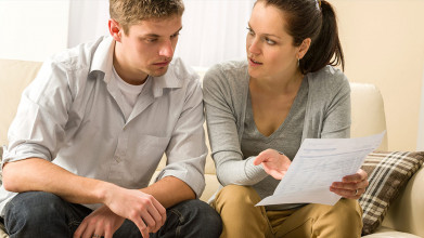 Young married couple sitting on a couch discussing financial issues
