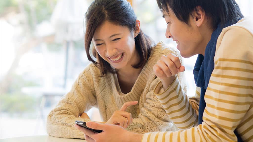 Laughing young Asian couple looking at a smartphone