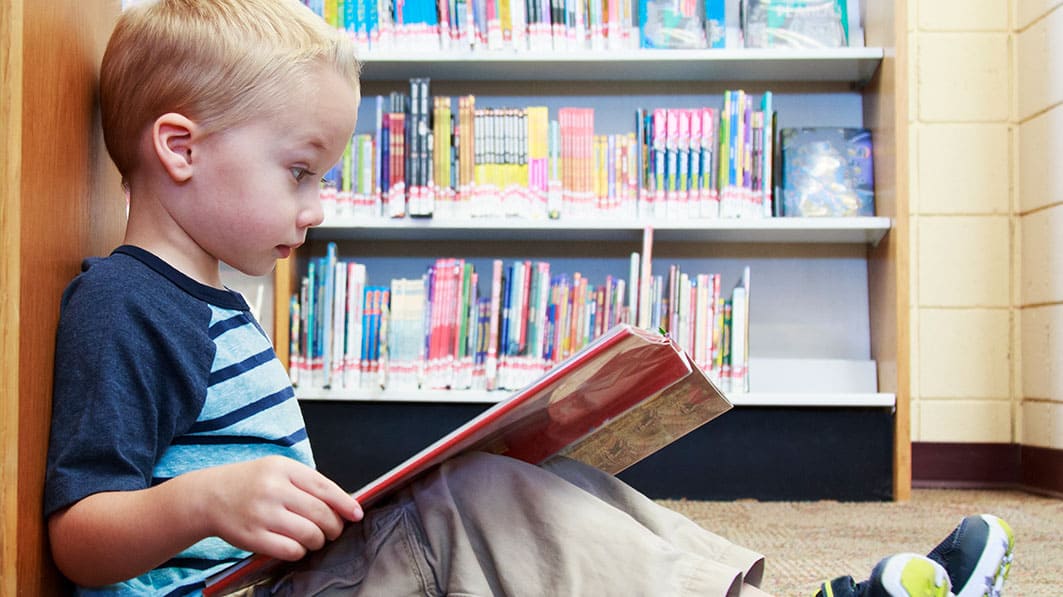 young boy reading a book, reading to children