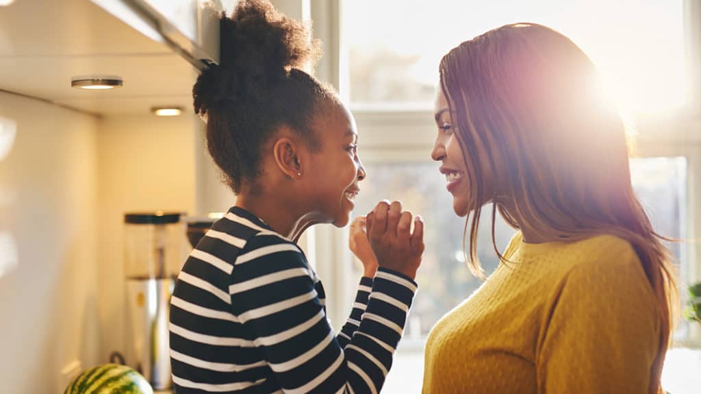 Young happy African American girl face to face with her smiling mom