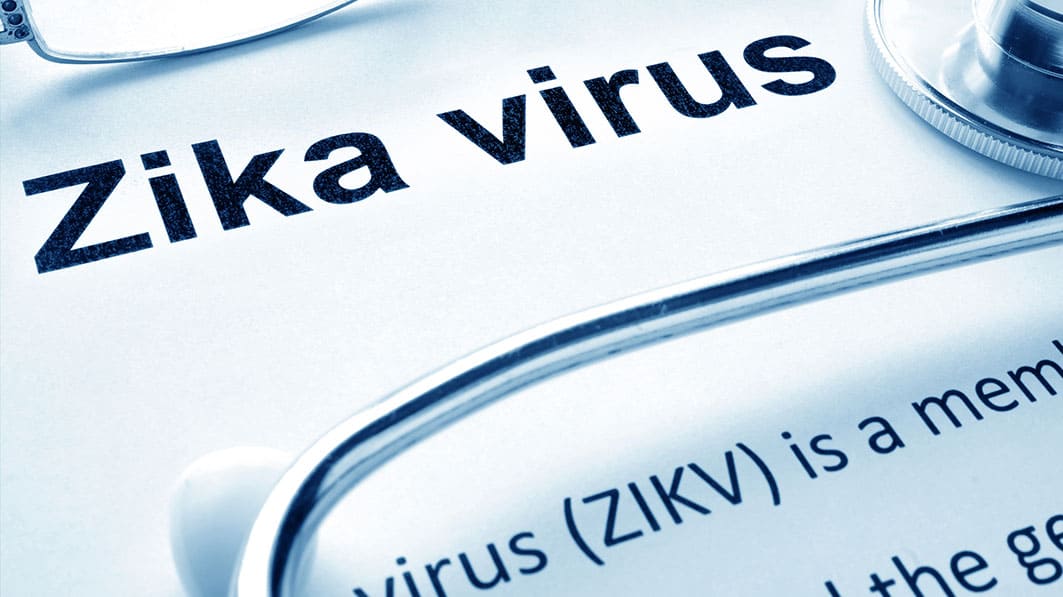 Close up of the words "Zika virus" on a white background surrounded by glasses and a stethoscope and a partial definition of the virus