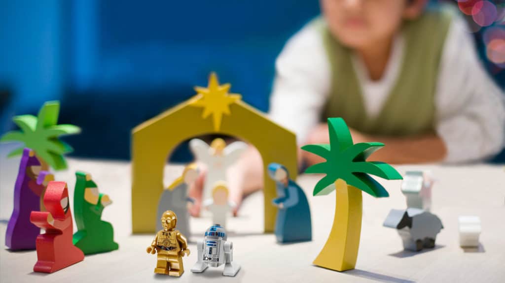 Close up of small, wood-carved Nativity scene with two of the characters being Star Wars Lego figures C-3PO and R2D2