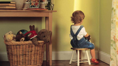 Young child being disciplined by sitting on a stool and facing the corner of a room