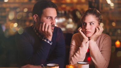 Young serious looking couple sitting in a restaurant with their heads resting on their hands