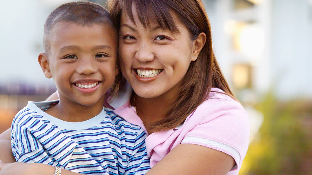 Close up of smiling mom hugging her smiling, young son, posing for the camera.