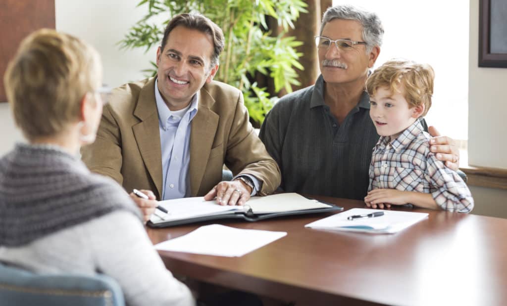 A Planned Giving Consultant smiles while speaking with grandparents and their grandchild