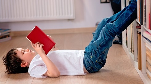 boy lying on floor reading a book