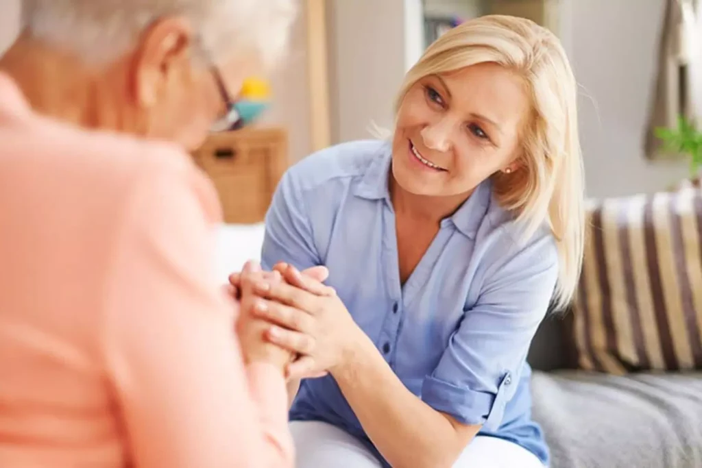 A woman gently holds the hands of an elderly parent, symbolizing the compassion and dedication involved in caring for elderly parents.