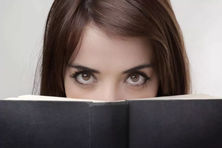 Woman looking intensely over a black covered book.