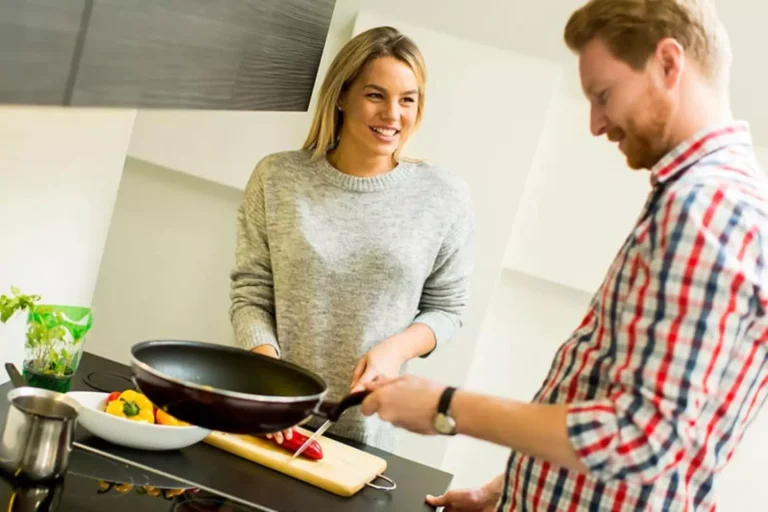 A couple cooking together in the kitchen, smiling and interacting warmly, illustrating the concept of giving grace to your spouse.