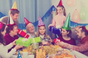 Multigenerational family celebrating a child’s birthday together with gifts, party hats, and festive decorations.