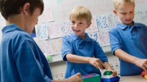 Three young boys in a classroom, happily doing a hands-on activity at a table