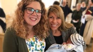 Two smiling women holding an infant