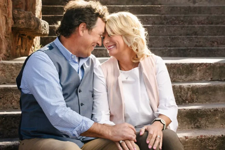 Al and Lisa Robertson smiling and being affectionate as they sit together on some steps