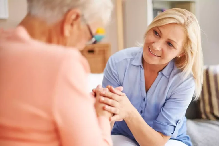 A compassionate caregiver holds hands with an elderly woman, offering support and warmth, symbolizing the importance of preventing caregiver burnout.