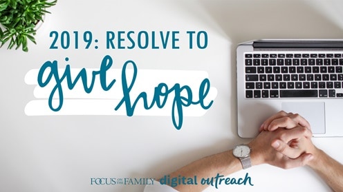 Folded prayer hands over a computer with the text 2019: Resolve to Give Hope