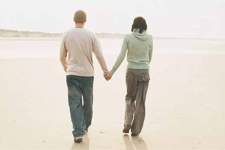 A couple walking hand in hand on the beach, symbolizing trust, unity, and the concept of submitting to your husband in a healthy, respectful marriage.
