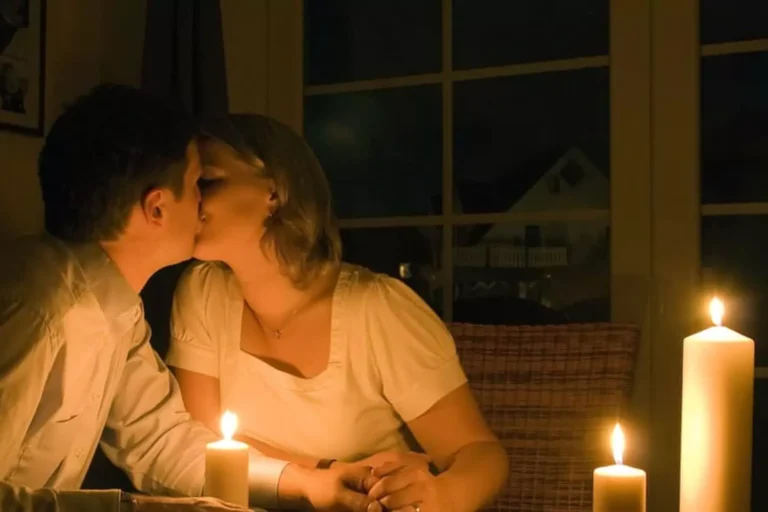 A couple sharing a kiss at a candlelit dinner table, symbolizing the essence of true romance in an intimate and serene setting.