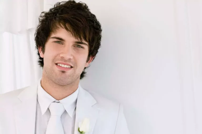 A groom in a white suit smiling confidently, representing qualities to look for in a future husband.