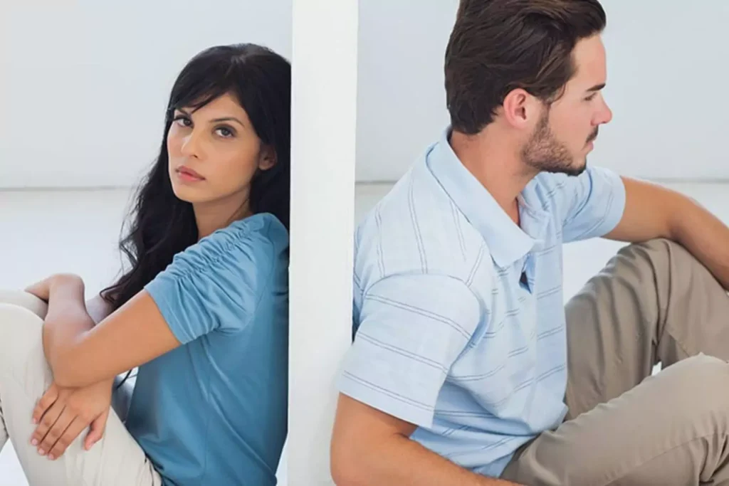 A couple sitting back-to-back separated by a wall, portraying the emotional disconnect often felt when your spouse is emotionally distant.