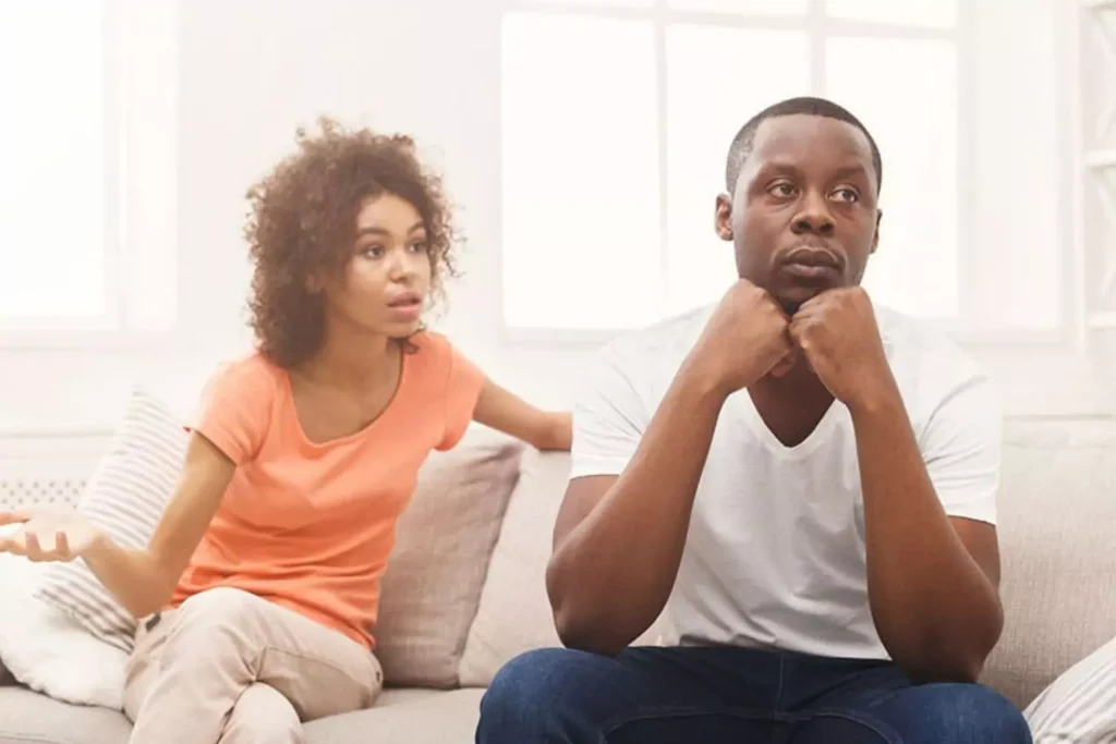A couple having a tense conversation at home, capturing emotional strain and disconnection that can occur when your spouse has past trauma.