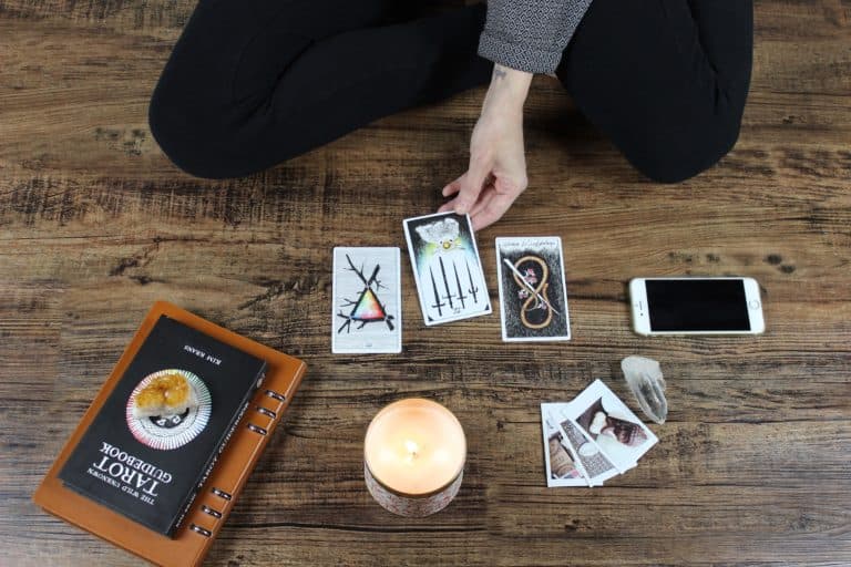 Young woman using Wicca artifacts like tarrot card, cell phone, book and candle
