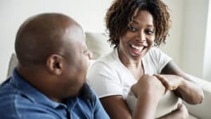 Smiling black couple sitting on a couch, giving each other a fist bump