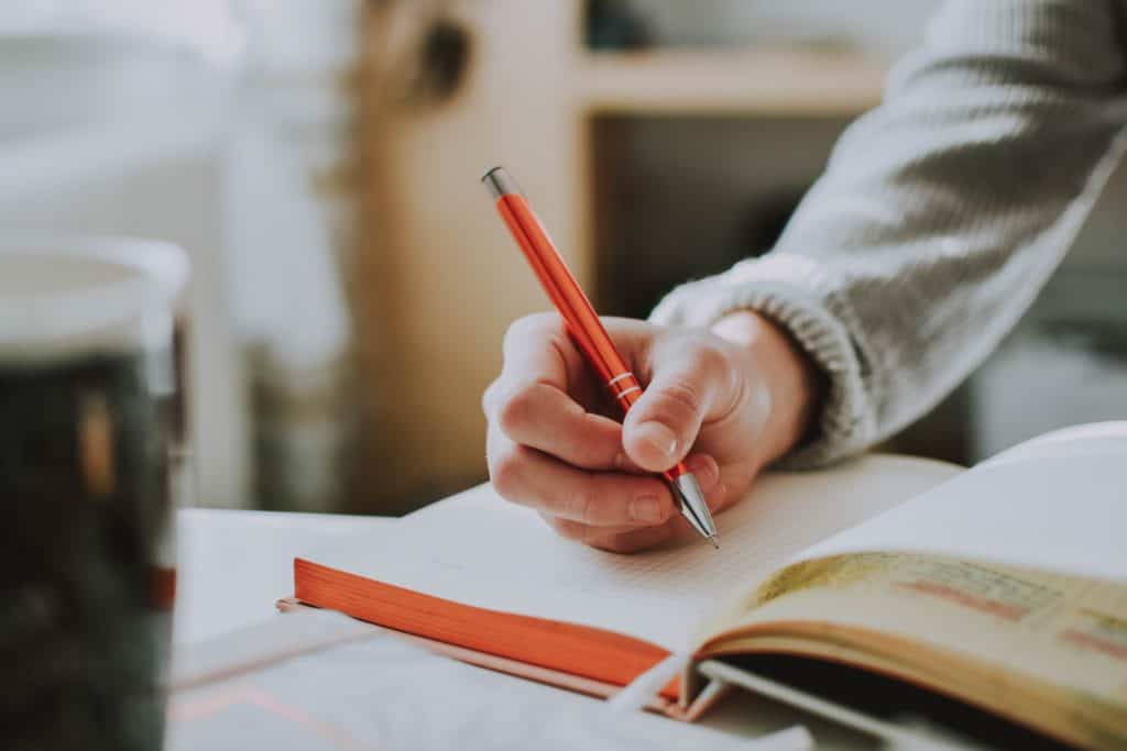 A man is writing in a journal to stay connected to his family through a journal.