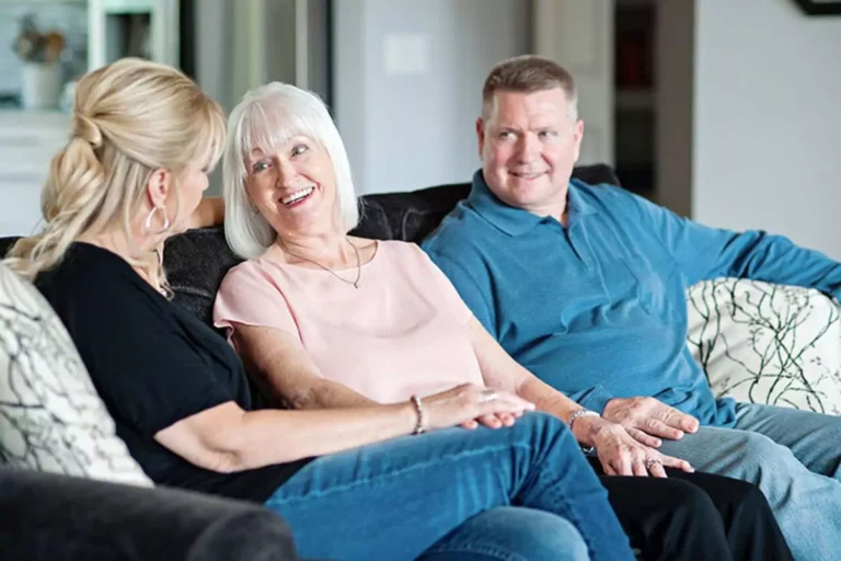 A smiling family gathered on a couch, reflecting the love and commitment involved in caring for aging parents.