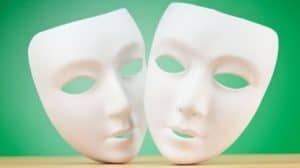 Two white full face masks stood up on a table with a green background