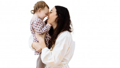 Mom Holding Daughter: a loving mom holds her young daughter against a white wall