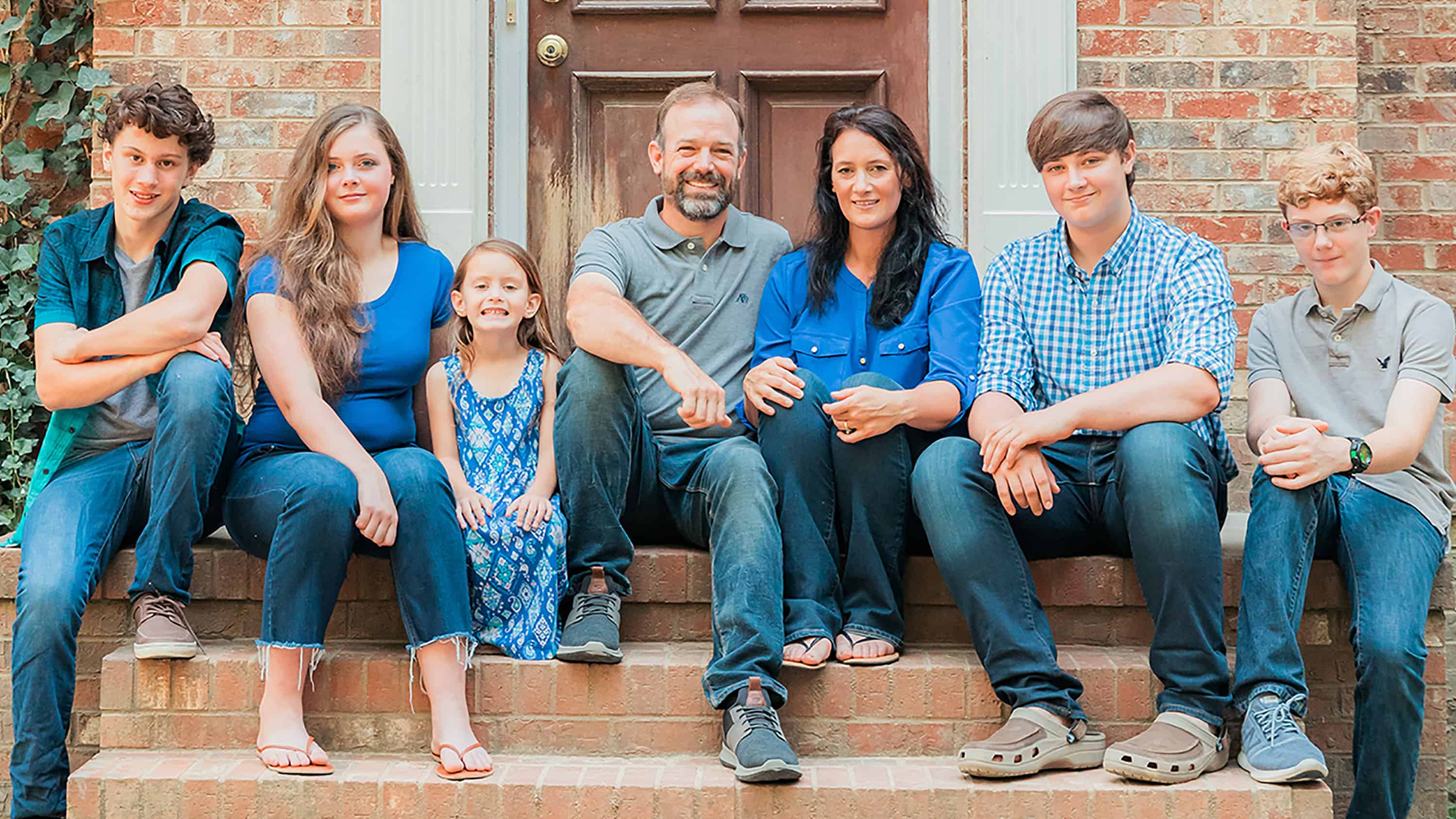 Family of seven sitting on porch steps