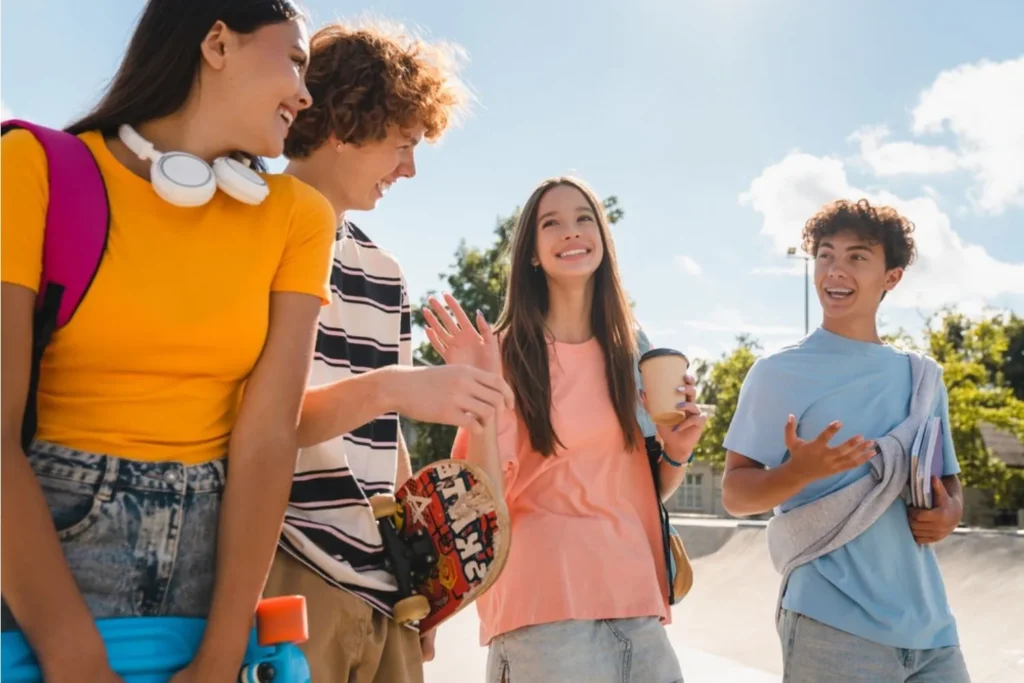 Two teen girls and two teen boys walking and talking together outdoors