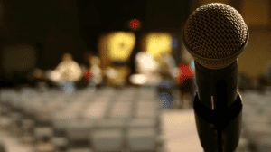 Close up of microphone with mostly empty auditorium in the background