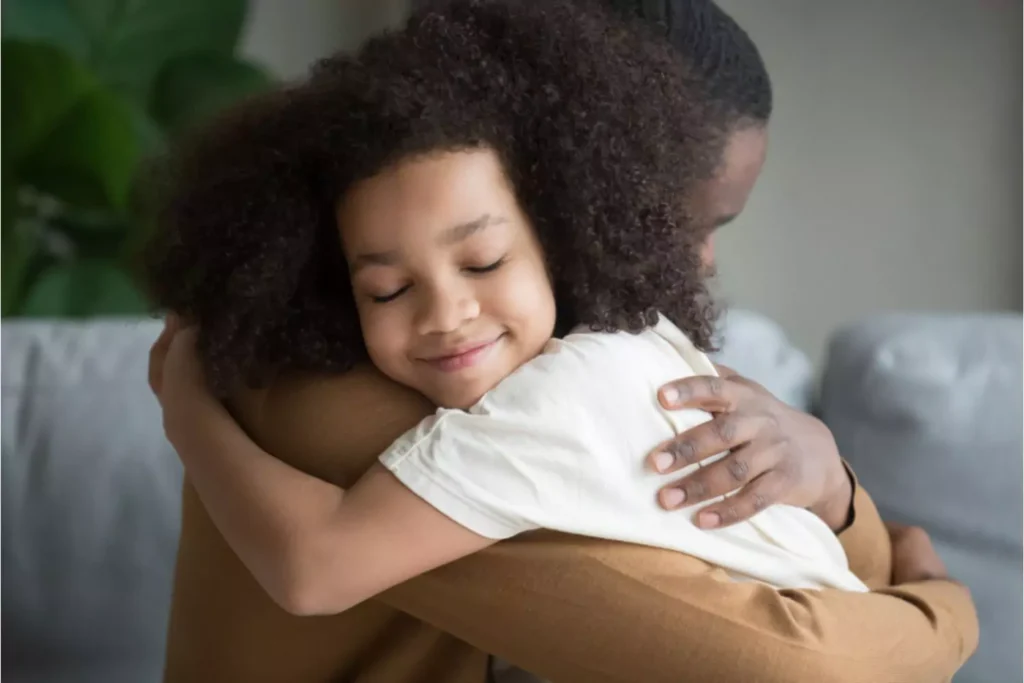 School age girl smiling and hugging her father.