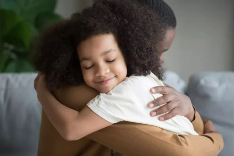 School age girl smiling and hugging her father.