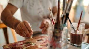 a painter pours paint onto a canvas